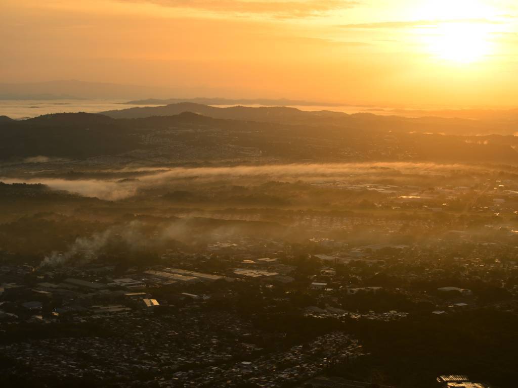 El sol ilumina la ciudad cubierta de neblina al amanecer.