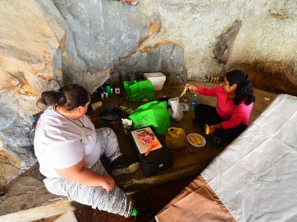 Dos personas cocinan el desayuno para el grupo en la mañana.