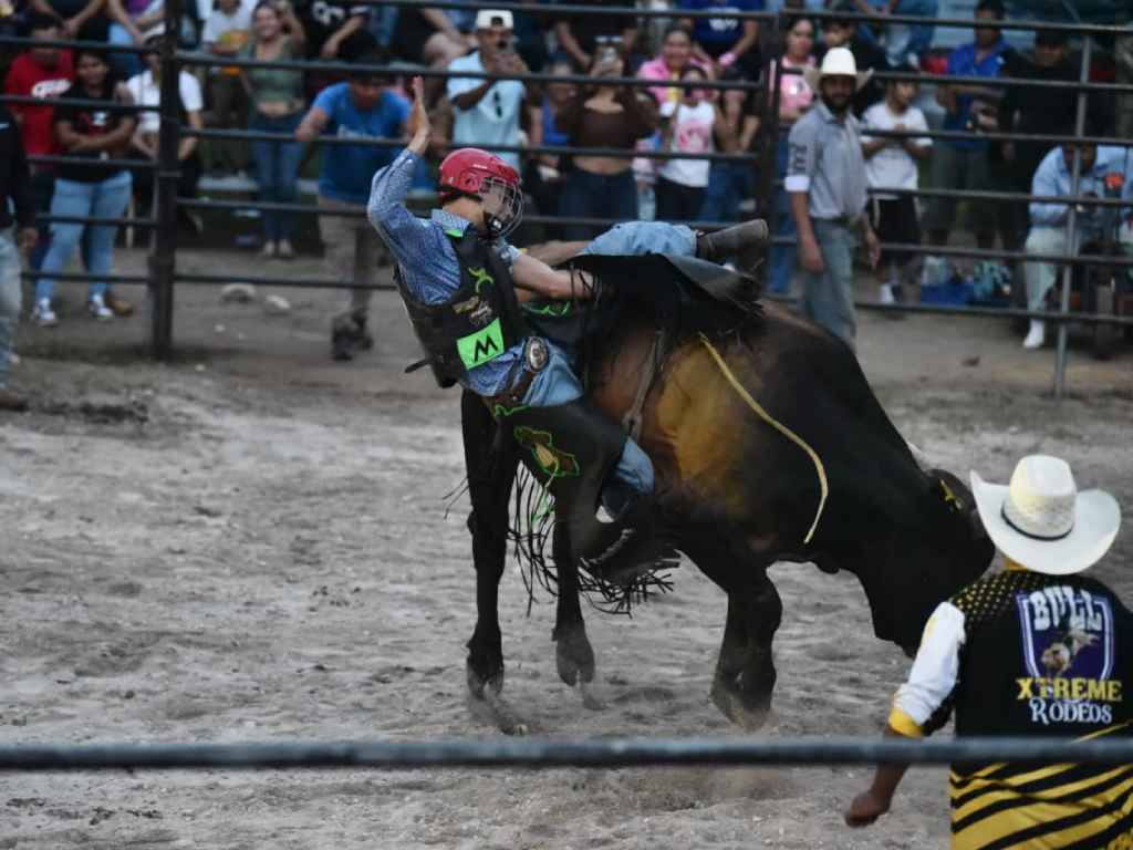 Jinete pierde el equilibrio sobre un toro en pleno rodeo.