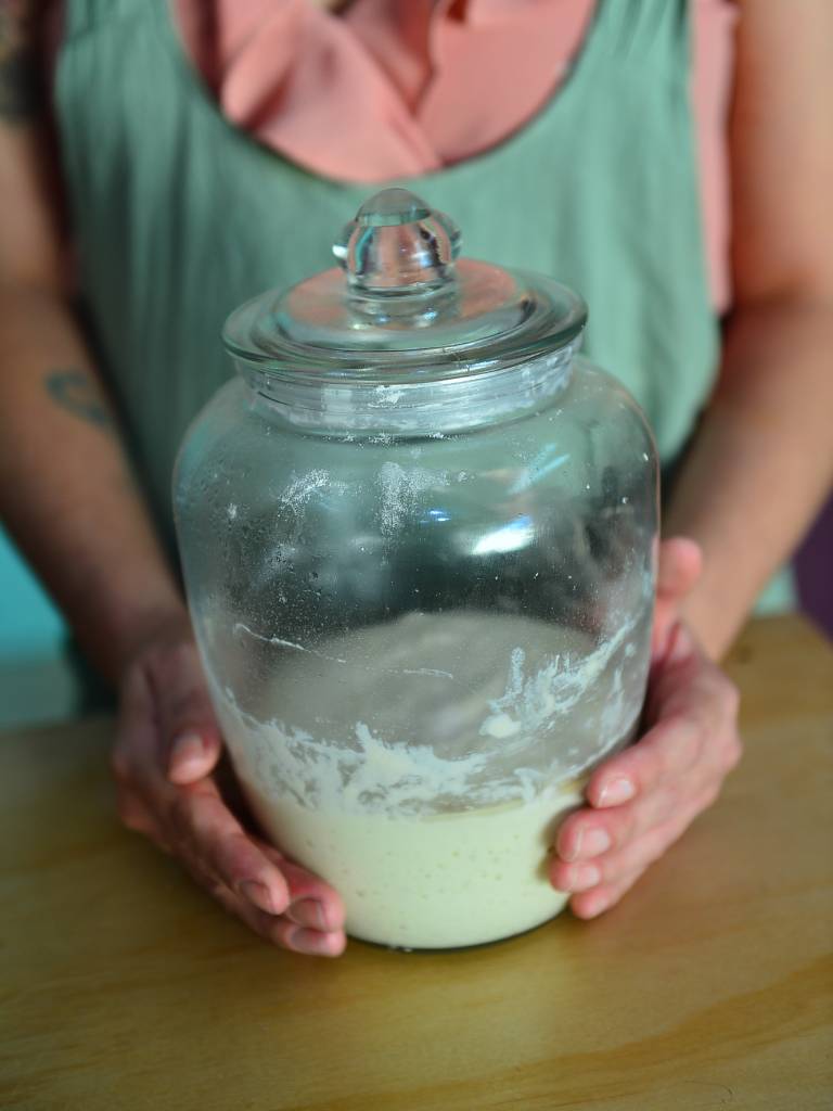 Mano sosteniendo un pan artesanal de masa madre recién horneado.