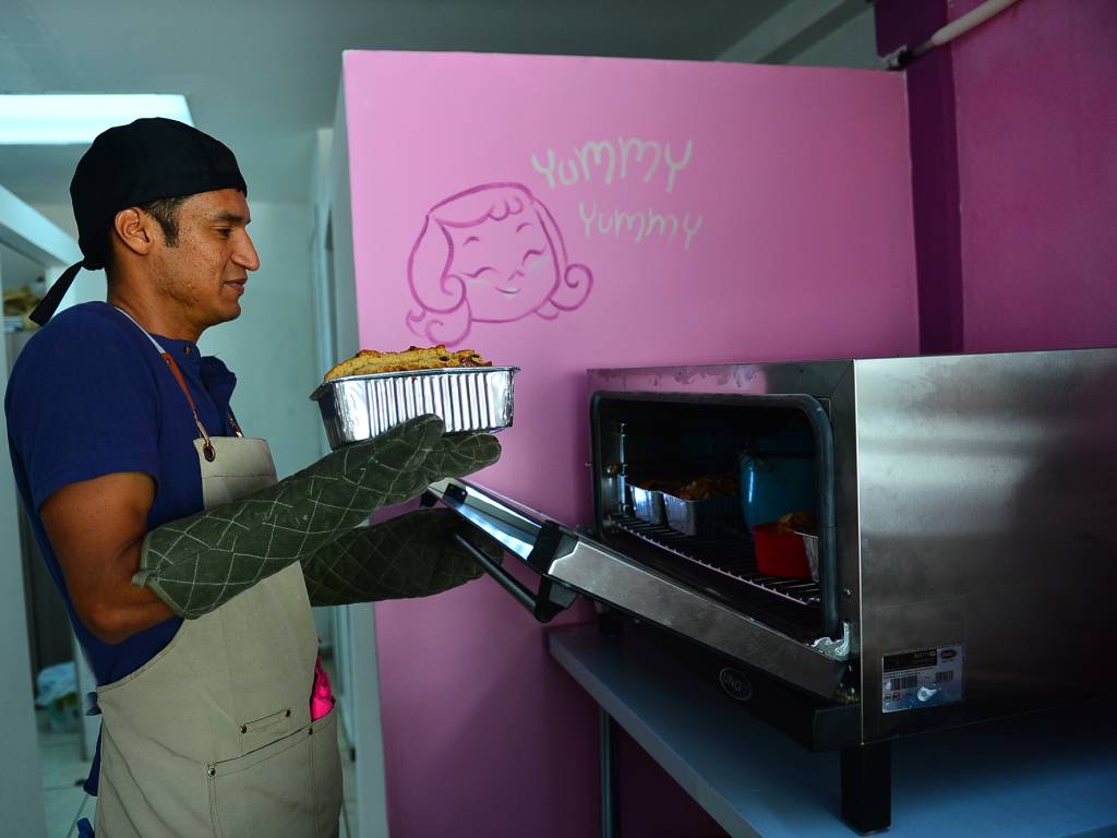 Hugo ayuda a sacar una bandeja de pan crujiente del horno.