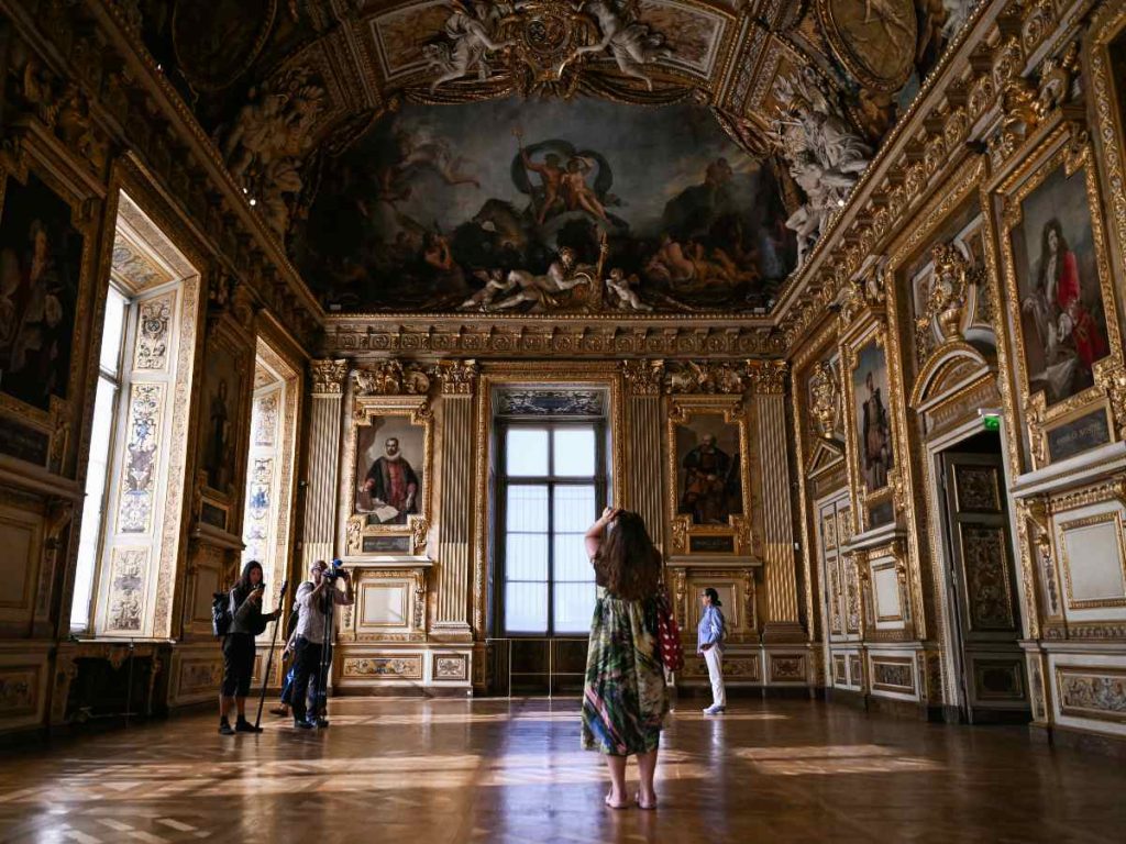 Visitantes fotografían la ventana dañada durante la reapertura de la Galería de Apolo del Museo del Louvre.