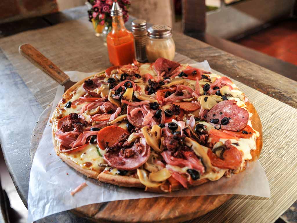 Pizza grande con jamón, salami y aceitunas negras.
