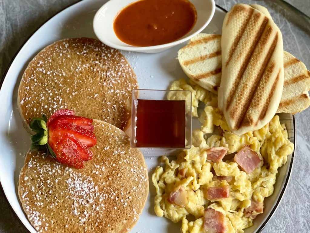 Plato con pancakes, huevo, jamón y pan tostado en Santein.