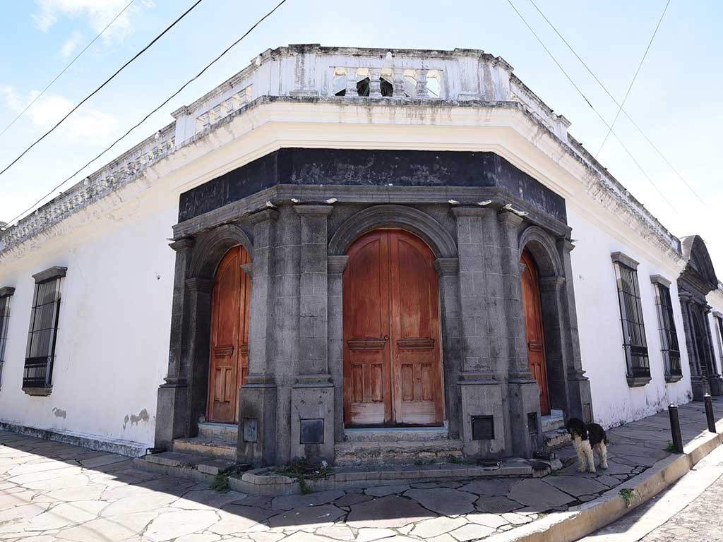 Casa colonial del Teatro Alejandro Cotto con puertas de madera arqueadas y paredes blancas en Suchitoto.