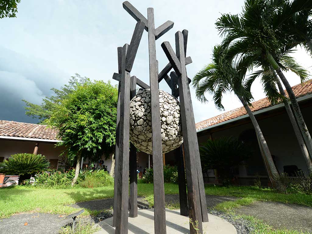 Escultura moderna de metal y piedra en un patio jardín en Suchitoto.