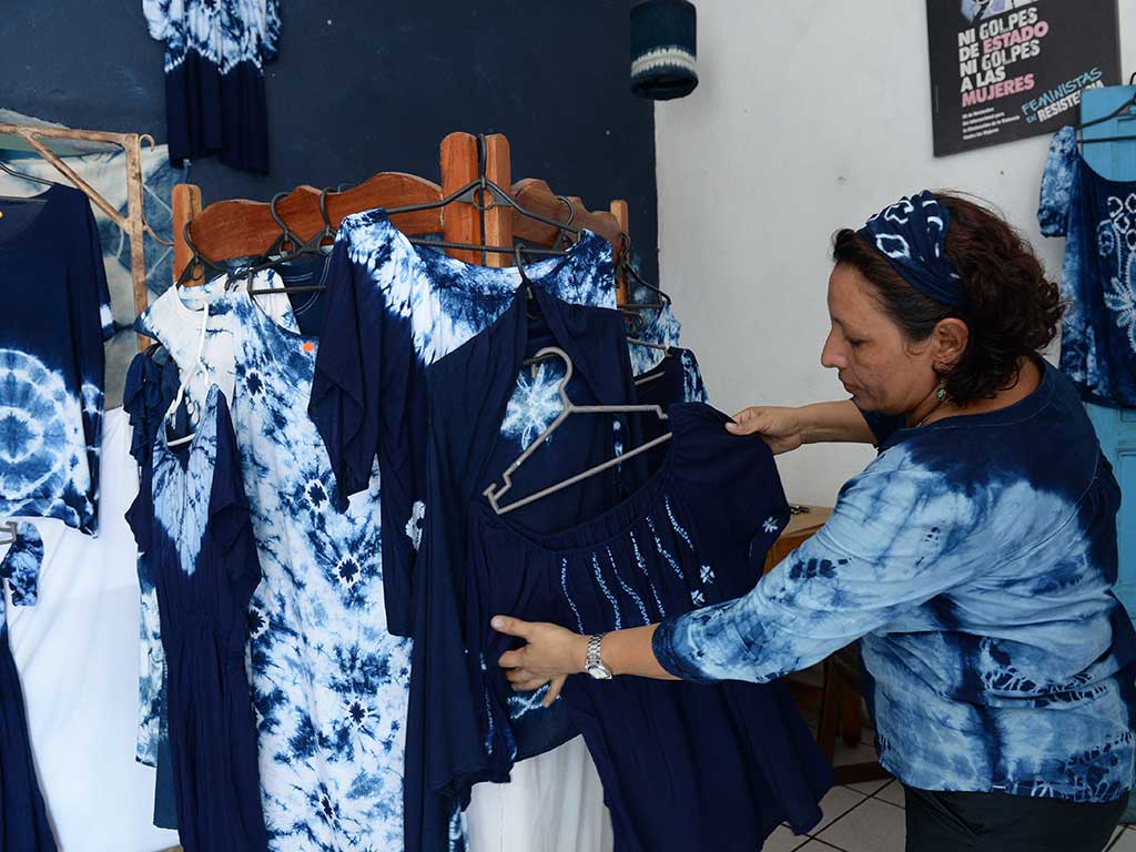 Mujer teñiendo ropa con añil en un taller artesanal en Suchitoto.