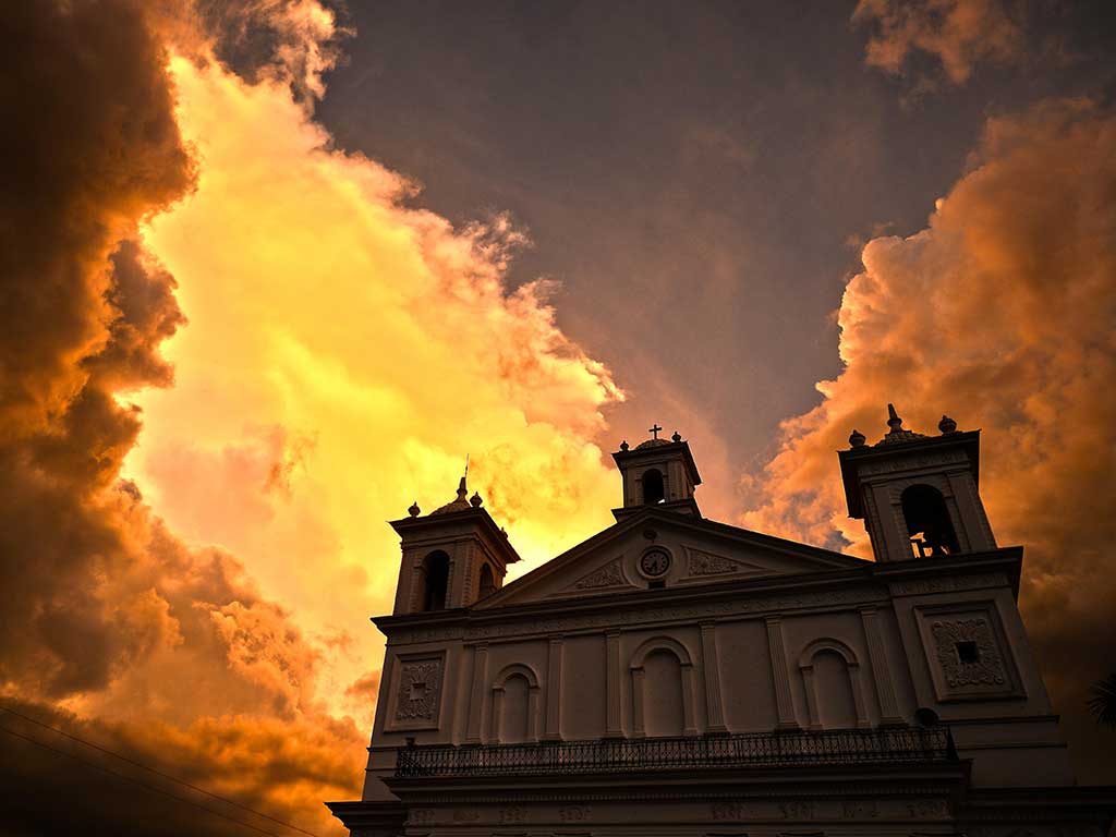 Iglesia de Suchitoto durante el atardecer con nubes dramáticas.