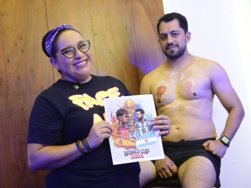Karlota Lota presenta el boceto que guió la creación del body paint mundialista sobre el torso de Manuel.