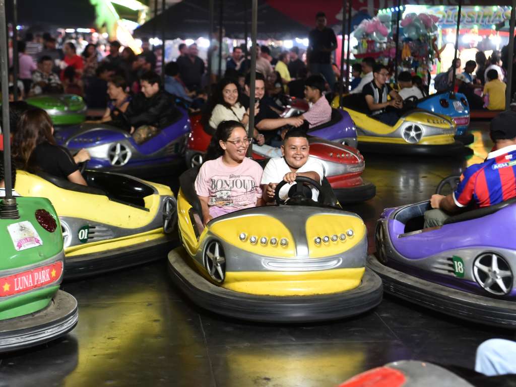 Niños y adultos se divierten conduciendo y chocando los coloridos autos eléctricos.