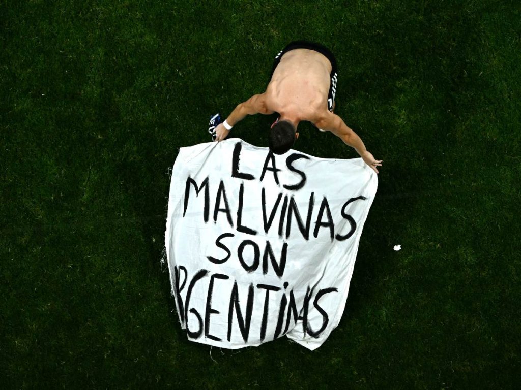 El mediocampista argentino Giovani Lo Celso, número 11, ajusta una pancarta que dice "Las Malvinas (Islas Falkland) pertenecen a Argentina", tras ganar el partido de semifinales del Mundial de Fútbol de 2026 entre Inglaterra y Argentina en el Estadio de Atlanta, el 15 de julio de 2026. (Foto de Jewel SAMAD / AFP)