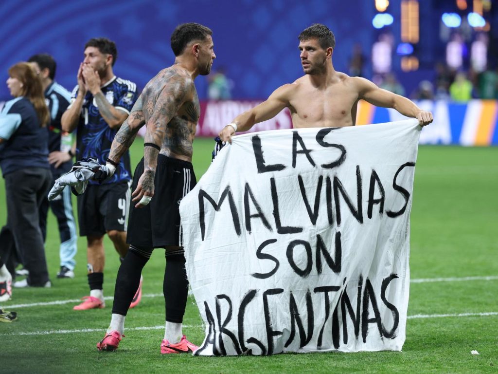 El defensa argentino número 19, Nicolás Otamendi (izquierda), y el mediocampista número 11, Giovani Lo Celso, muestran una pancarta que dice en español: 
