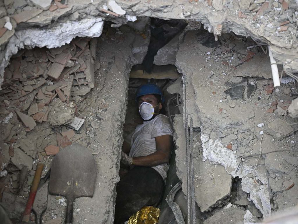 Una persona busca cuerpos de víctimas entre los escombros de un edificio residencial que se derrumbó tras los terremotos del 24 de junio en Caraballeda, Venezuela, el 20 de julio de 2026. (Foto de Federico PARRA / AFP)