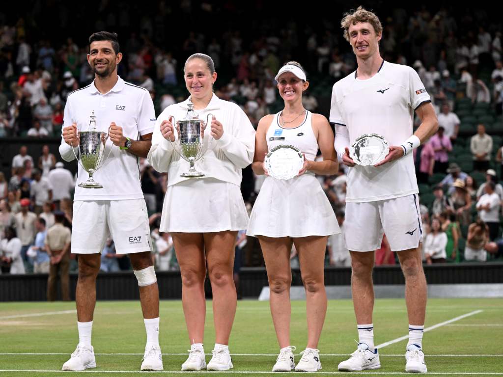 La clásica postal de la premiación en la cancha central. De izquierda a derecha, Marcelo Arévalo y Jelena Ostapenko posan muy sonrientes con sus copas de campeones; a su lado, la pareja subcampeona sostiene los tradicionales platos plateados de segundo lugar. Los cuatro lucen el estricto uniforme blanco del torneo.