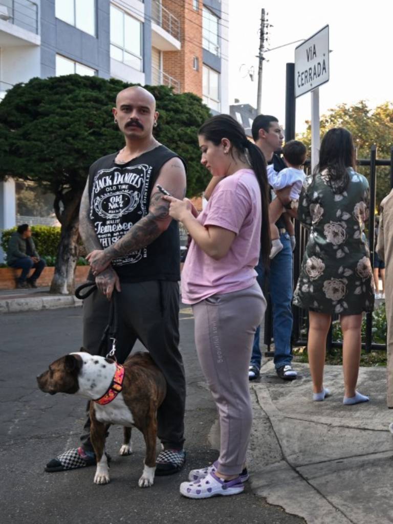 Grupo de vecinos congregados en la calle tras evacuar un edificio; destaca un hombre junto a su perro de raza pitbull.