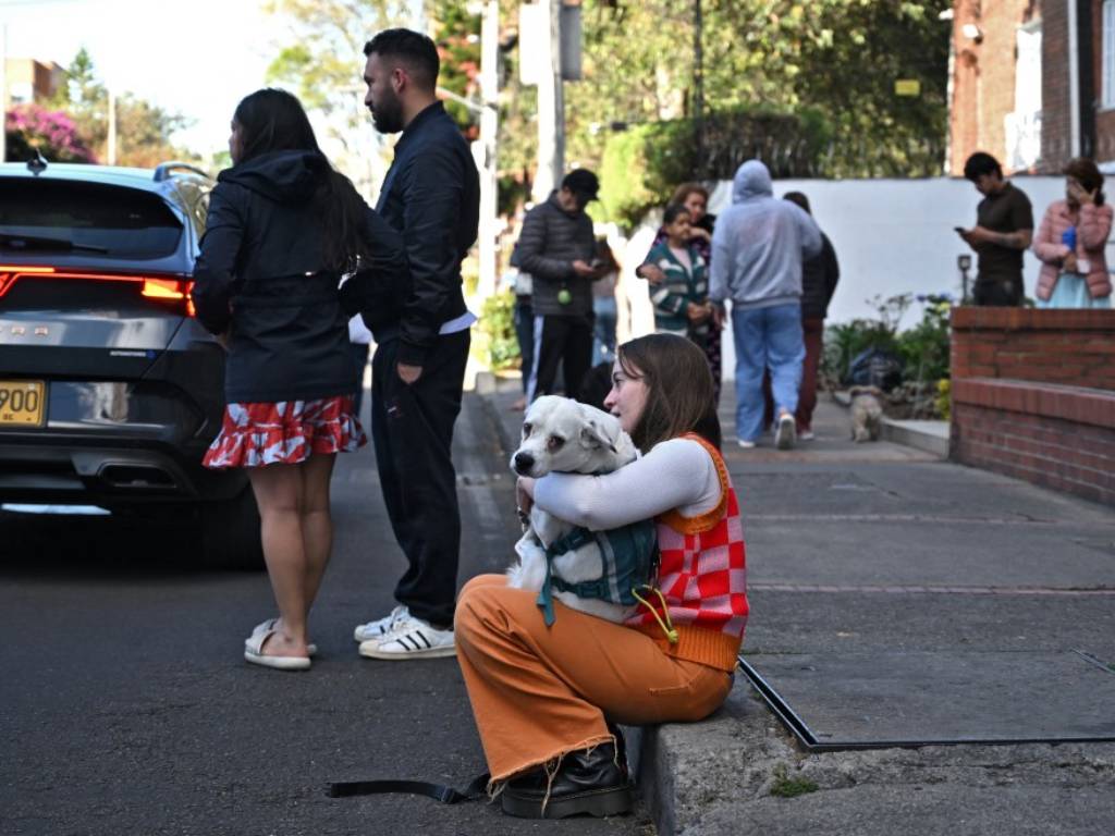 Joven sentada en la acera abraza conternada a su perro blanco tras el sismo.