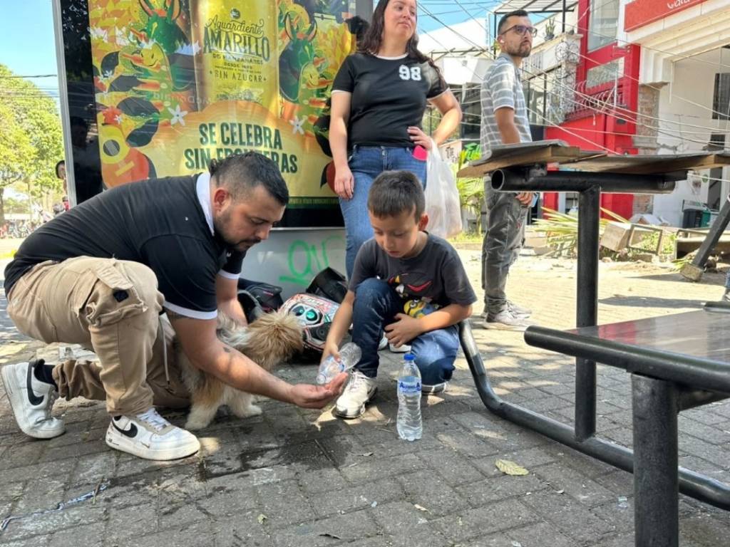 Tras salir del edificio, sus dueños le dan de beber agua a su mascota en Pereira, Colombia.