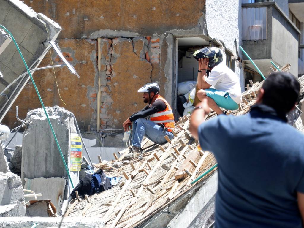 Grupo de personas observando los escombros de un edificio colapsado en Manizales.