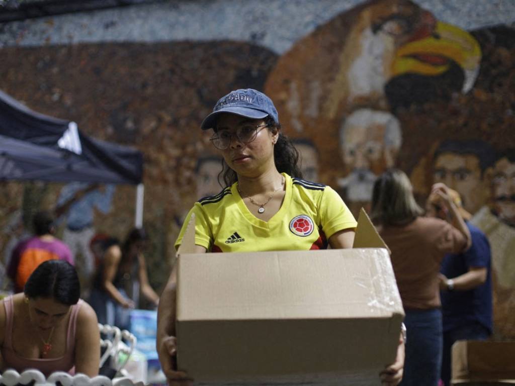 Voluntaria caminando por el centro de acopio mientras transporta insumos ya organizados.