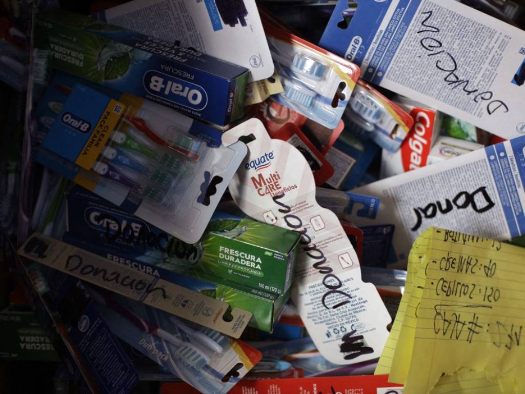 Caja llena de cepillos de dientes y pastas dentales empacados y marcados con la palabra donación.