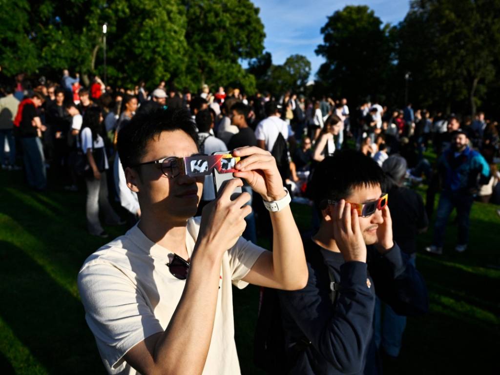 Varias personas observan a través de unas gafas especiales para eclipses durante el eclipse solar parcial en el parque Observatorielunden, en el centro de Estocolmo, Suecia.
