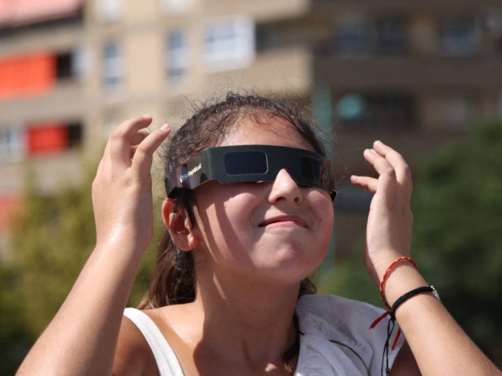 Persona con gafas de protección solar sobre el puente de Piedra en Zaragoza, lista para ver el eclipse.