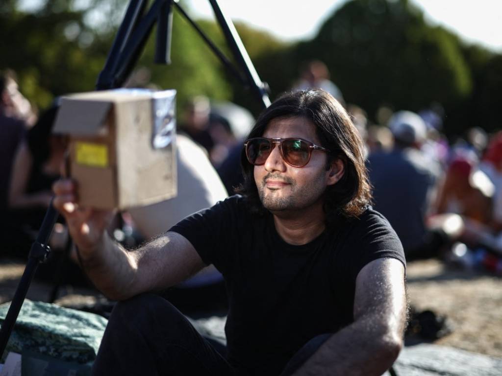 Varias personas reunidas en la colina de Primrose Hill en Londres miran hacia el cielo a la espera del eclipse solar.