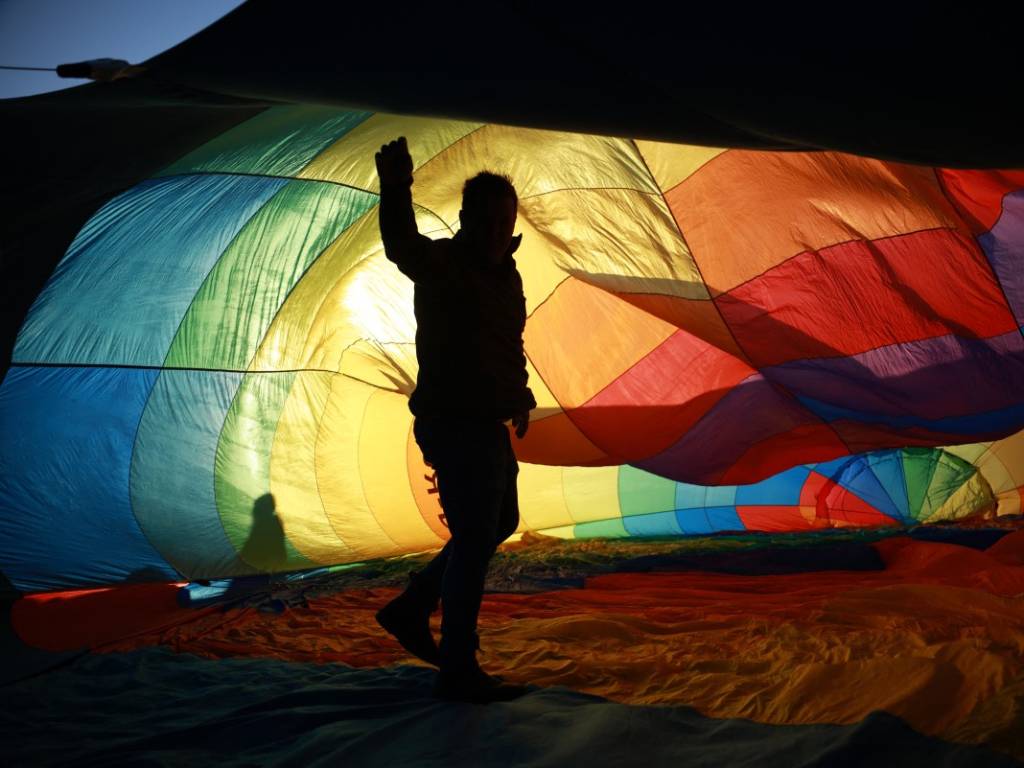 Silueta de una persona dentro de la lona multicolor e iluminada por el sol de un globo aerostático.