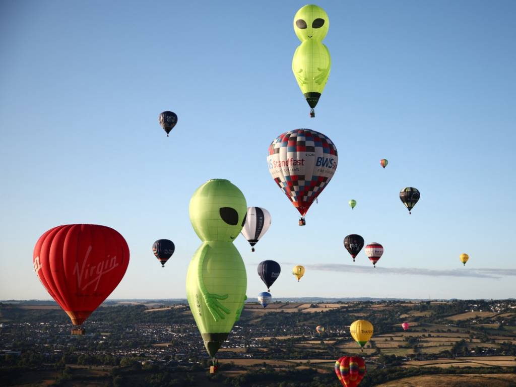Multitud de personas contemplando decenas de globos aerostáticos flotando en el cielo.