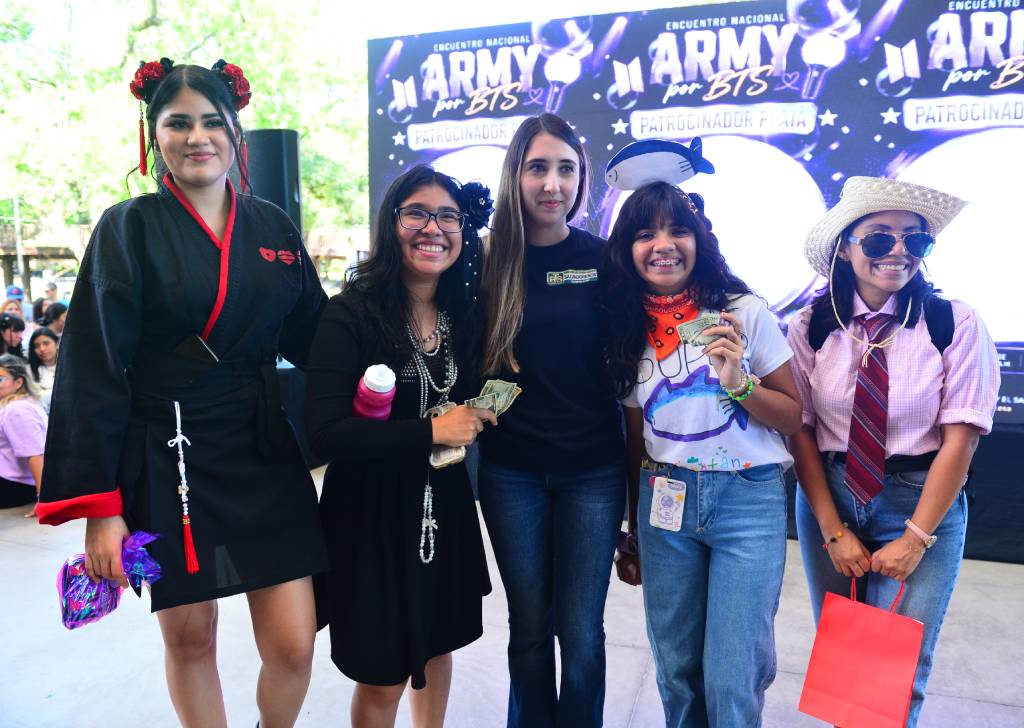 Cuatro fans de BTS luciendo sus vestuarios premiados en el escenario del evento.