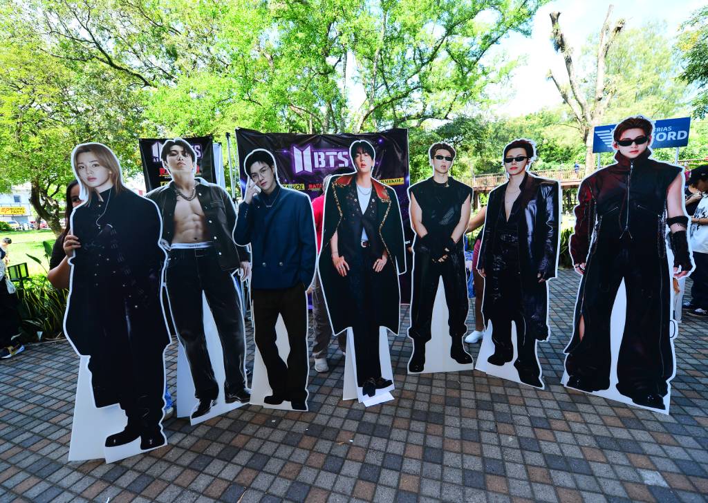 Gigantografías de los siete integrantes de BTS alineados de izquierda a derecha para tomarse fotografías.