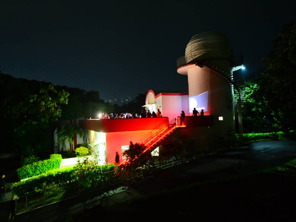 Persona mirando por el ocular de un telescopio apuntado hacia la Luna en una noche clara.