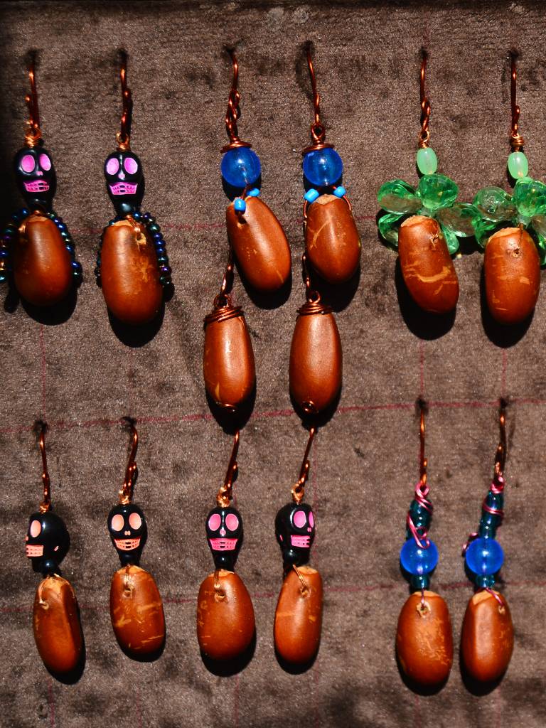 Par de aretes artesanales elaborados con semillas de anona expuestos para la venta.