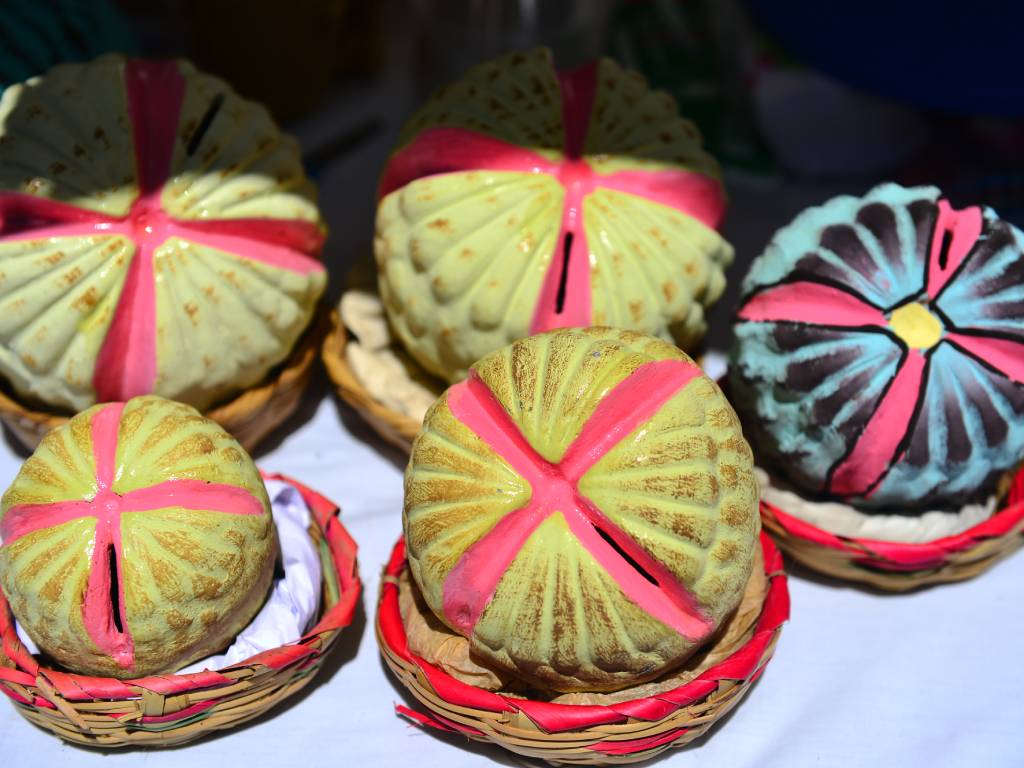 Alcancía de barro moldeo con forma de anona pintada a mano expuesta para la venta.