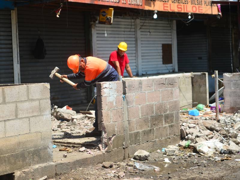 Operario con mazo golpeando repetidamente una pared de concreto para demolerla en medio de escombros.
