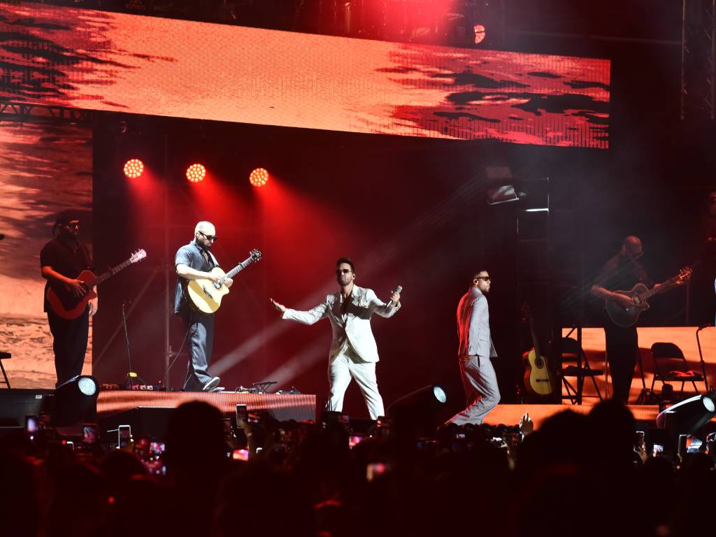 Prince Royce sonriendo mientras canta en el escenario iluminado del Estadio Cuscatlán.