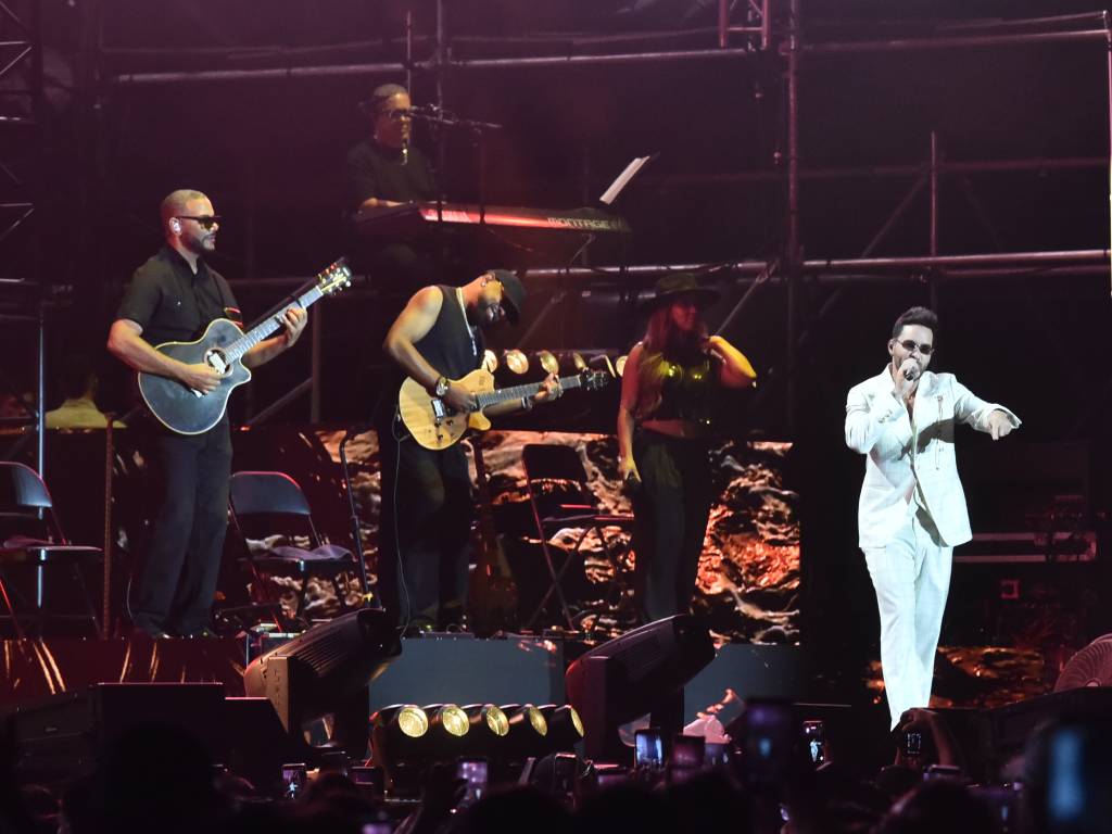 etrato de cerca de Prince Royce mirando a la cámara y sonriendo con un micrófono en la mano.