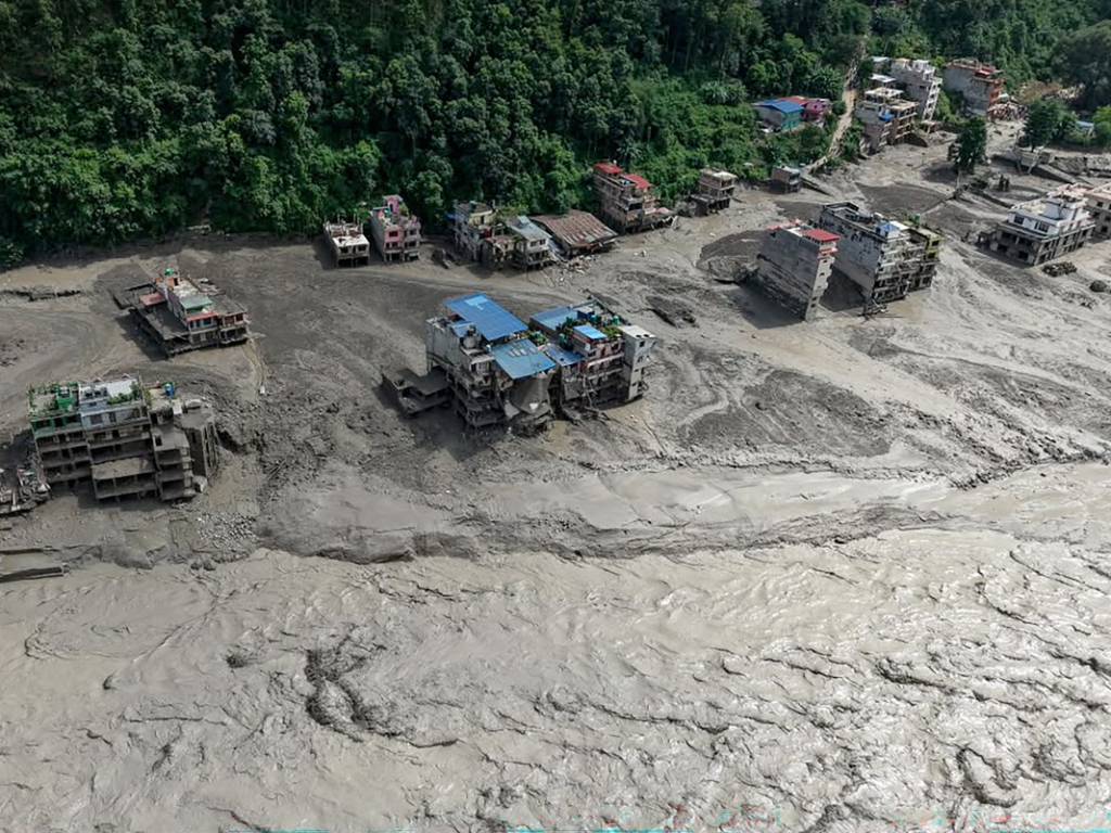 Varias viviendas inundadas y cubiertas de barro en la orilla de un río desbordado.