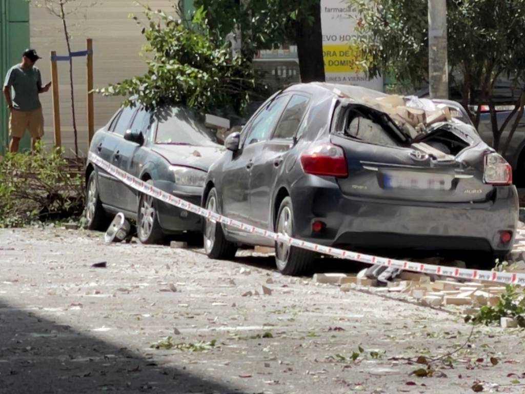 Vehículos cubiertos por cascotes y partes de fachada caídas a la vía pública tras el terremoto.