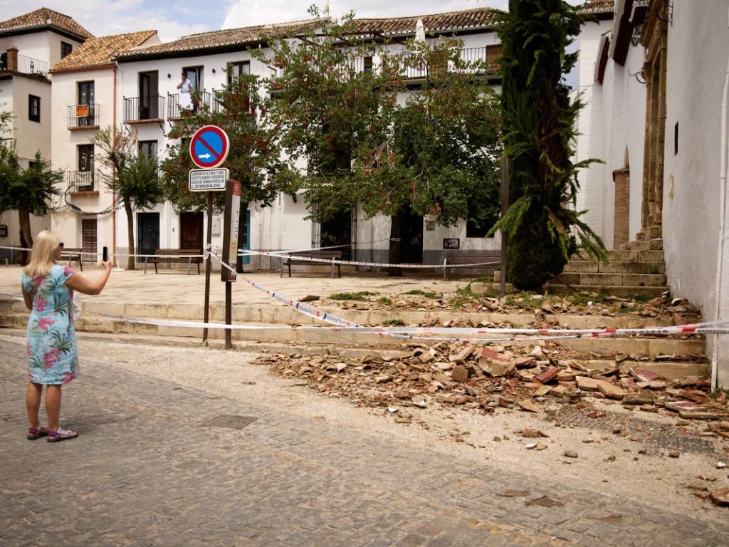 Turista con un teléfono móvil tomando fotos de las baldosas fracturadas en el suelo de la iglesia.
