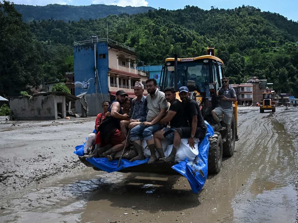 El personal de rescate transporta a los residentes atrapados utilizando una excavadora tras las inundaciones repentinas en la zona de Devighat, en el distrito de Nuwakot de Nepal, el 27 de agosto de 2026.