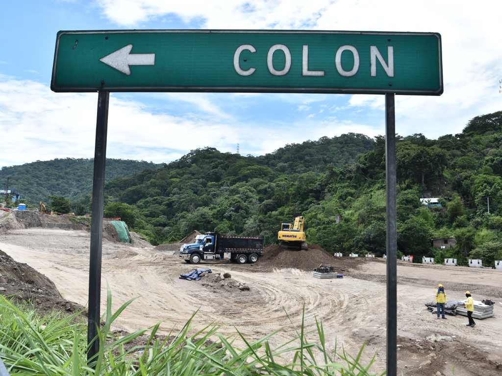 indica la dirección a Colón frente a una zona de movimiento de tierras y maquinaria.