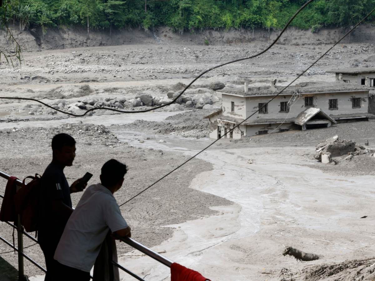 Varias personas observan cómo las aguas de la inundación arrasan Trishuli Bazar tras una crecida repentina, en el distrito de Nuwakot, Nepal, el 26 de agosto de 2026.