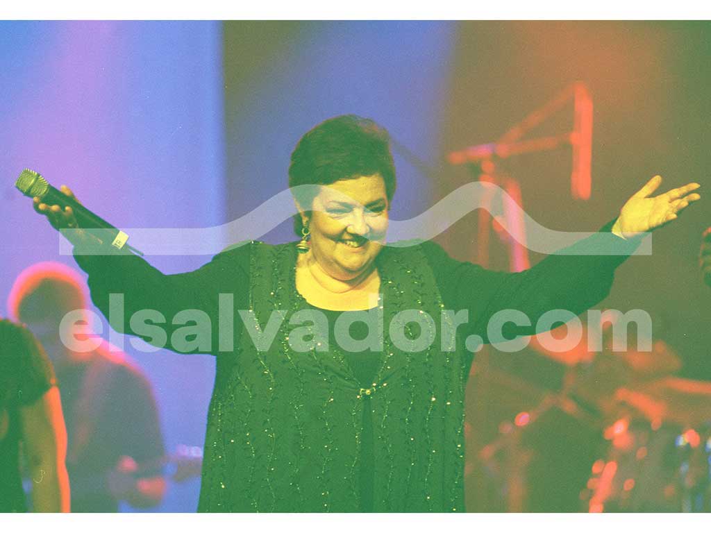 Amaya Uranga sonriendo alegremente con los brazos abiertos hacia el público sosteniendo un micrófono.