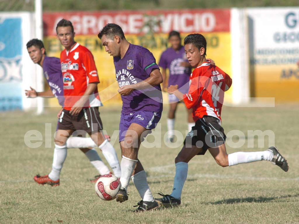 Una fotografía a color que captura a un jugador de Arcense con su uniforme azul y amarillo, saltando para cabecear el balón durante un partido de la Liga Mayor.