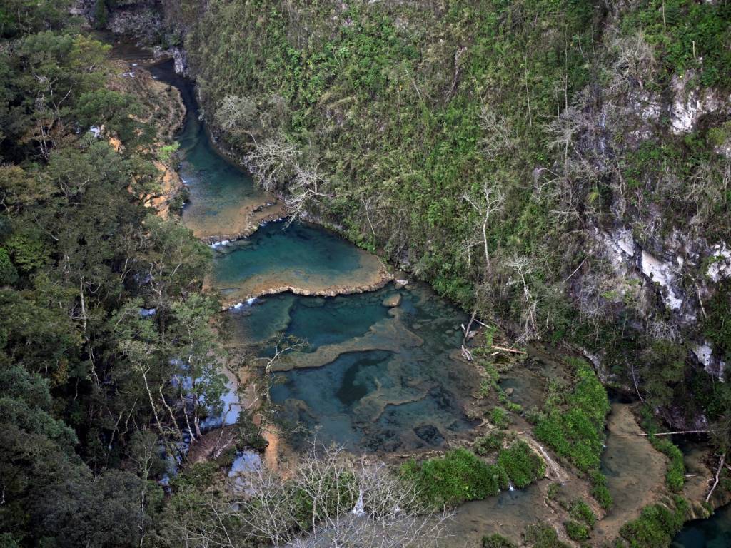 Pozas escalonadas de tono turquesa a verde esmeralda reposan sobre el puente, ideales para nadar.