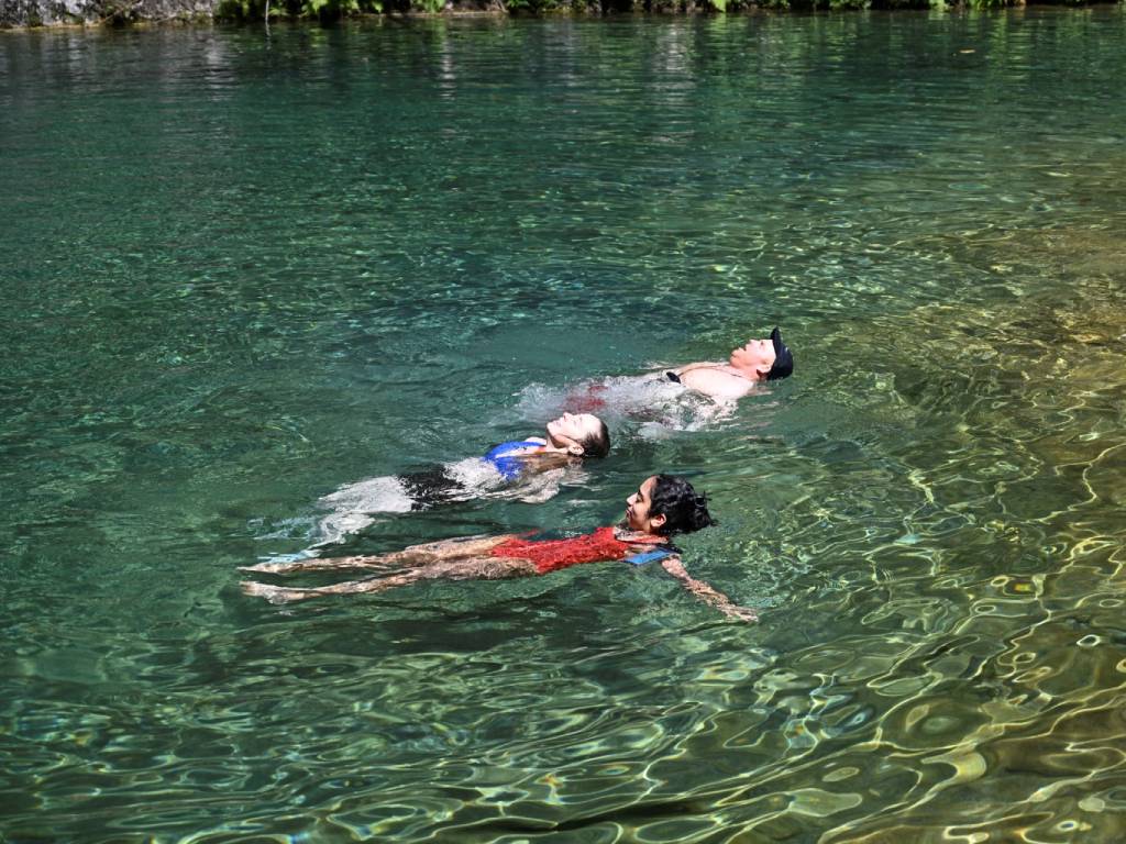 Pozas de agua cristalina exhibiendo tonos de verde esmeralda y azul turquesa bajo la luz solar.