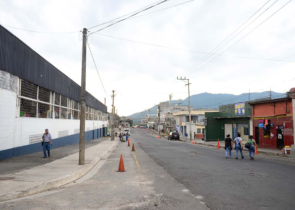 Perspectiva de una calle amplia y limpia con el edificio del Mercado Central a la izquierda y peatones transitando por la acera derecha.