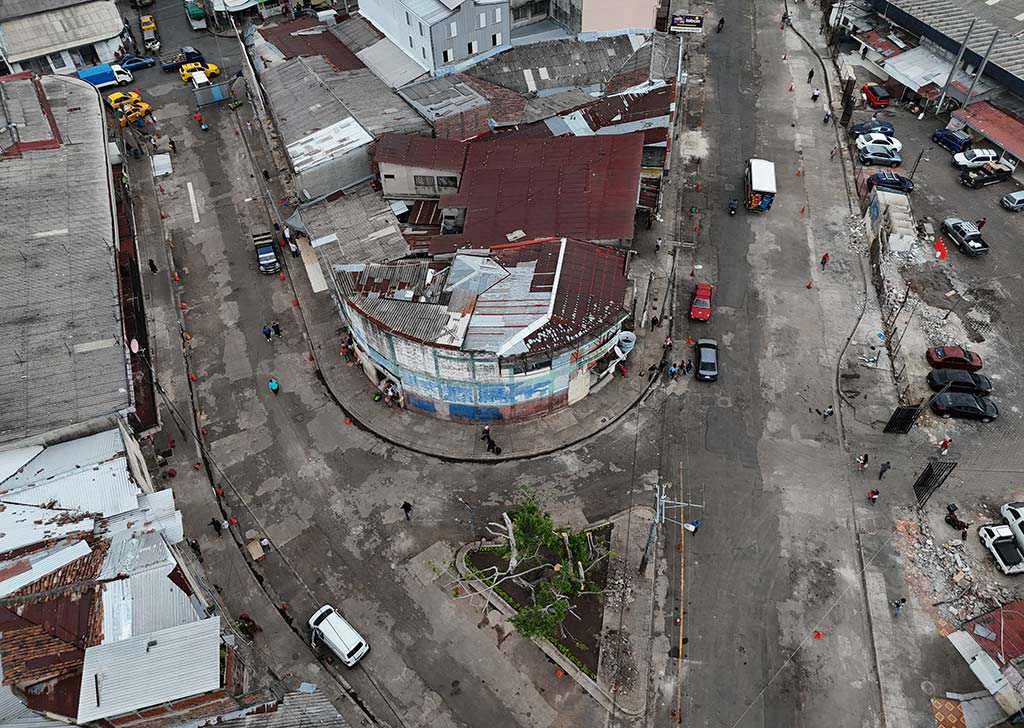 Fotografía aérea cenital de un bloque de edificios con techos de lámina rodeado por calles totalmente despejadas.