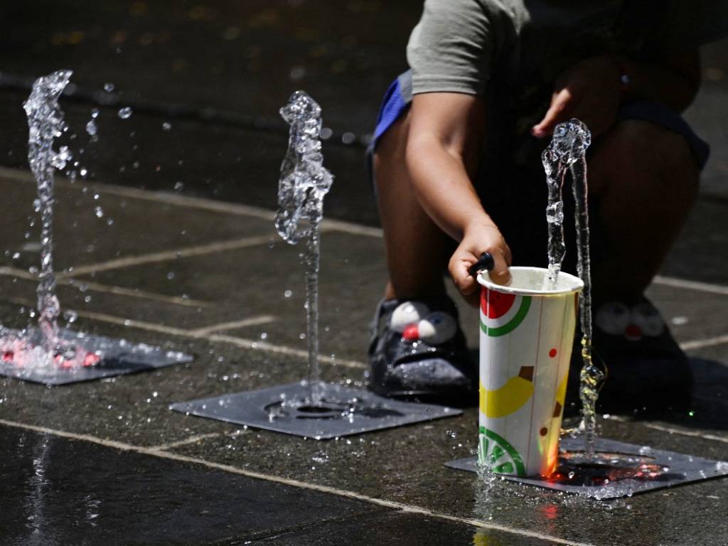 Un niño coloca un vaso sobre una fuente en el suelo.